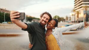 Closeup of smiling interracial couple taking a selfie on fountain background