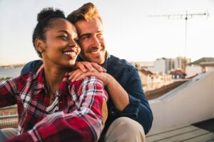 Happy affectionate young couple sitting on rooftop in the evening