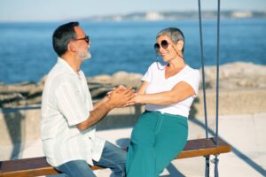 Happy European Couple On Swings Enjoying Summer At Ocean Outdoors